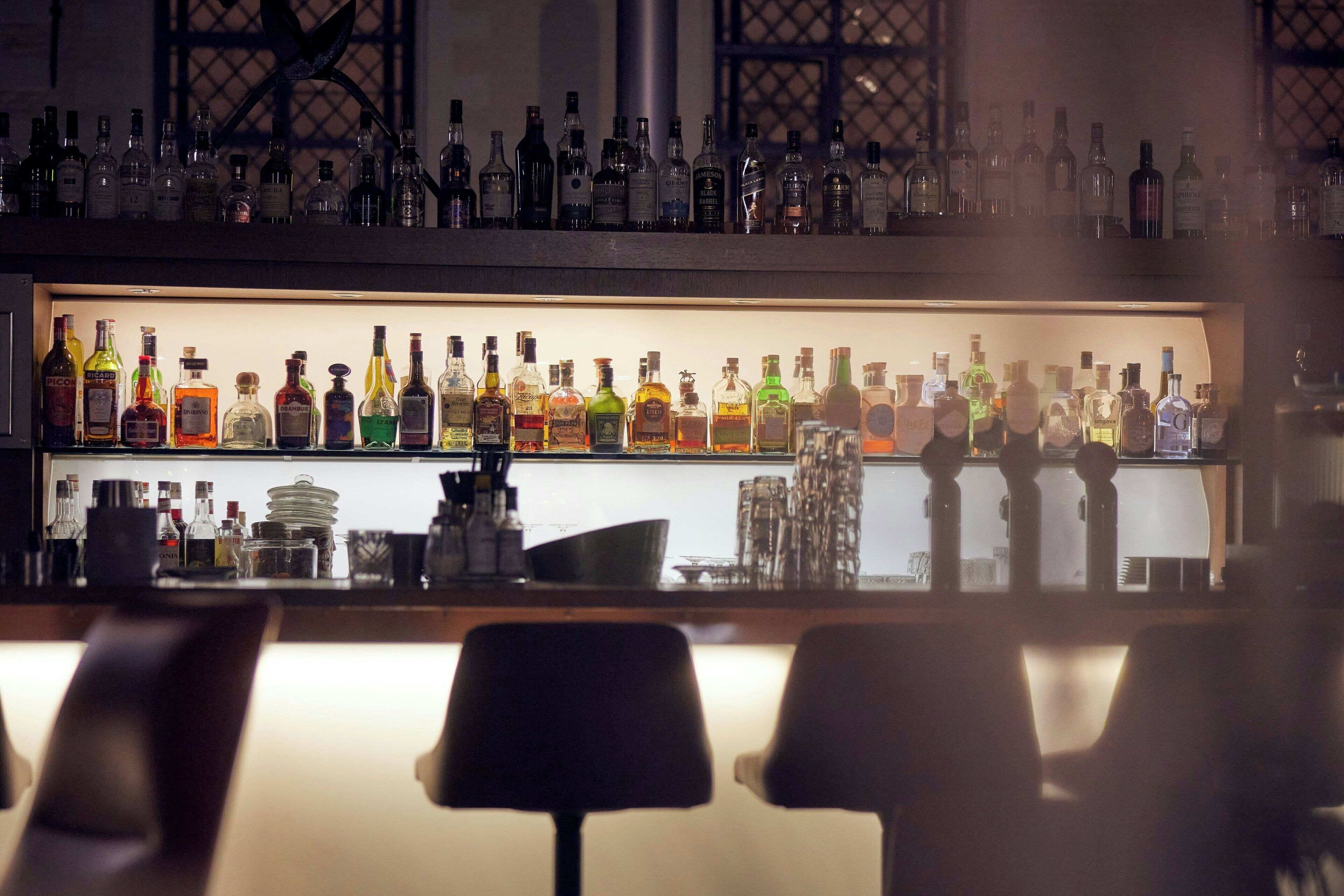 Een bar met planken vol verschillende drankflessen en glazen.