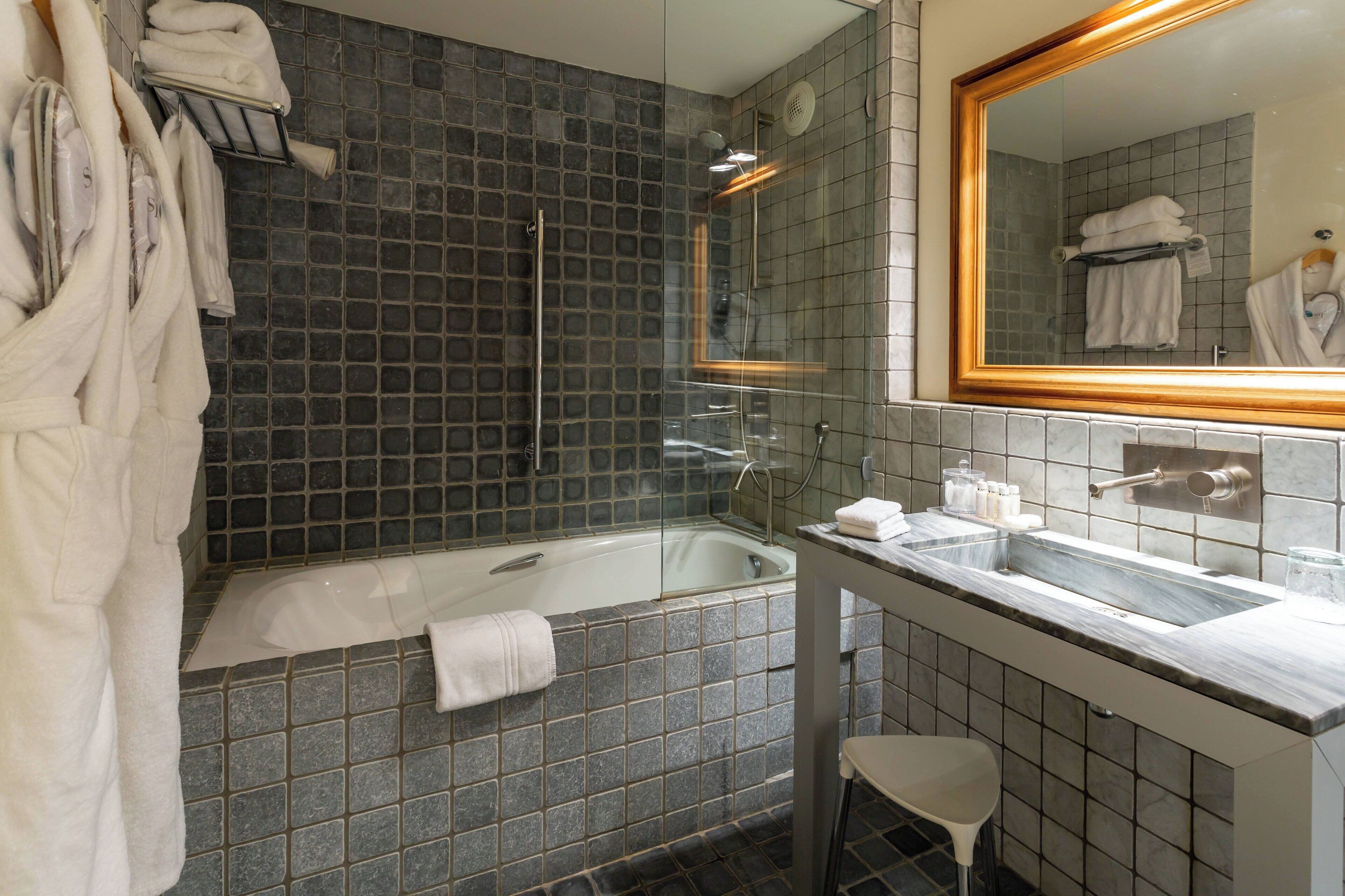 Une salle de bain moderne avec une douche à parois de verre, un lavabo en marbre et un grand miroir.