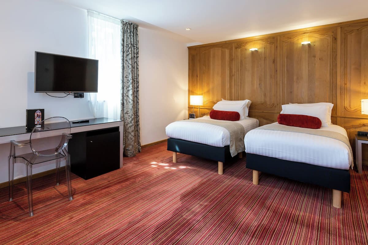Une chambre d’hôtel avec deux lits, un bureau, une télévision et une chaise.