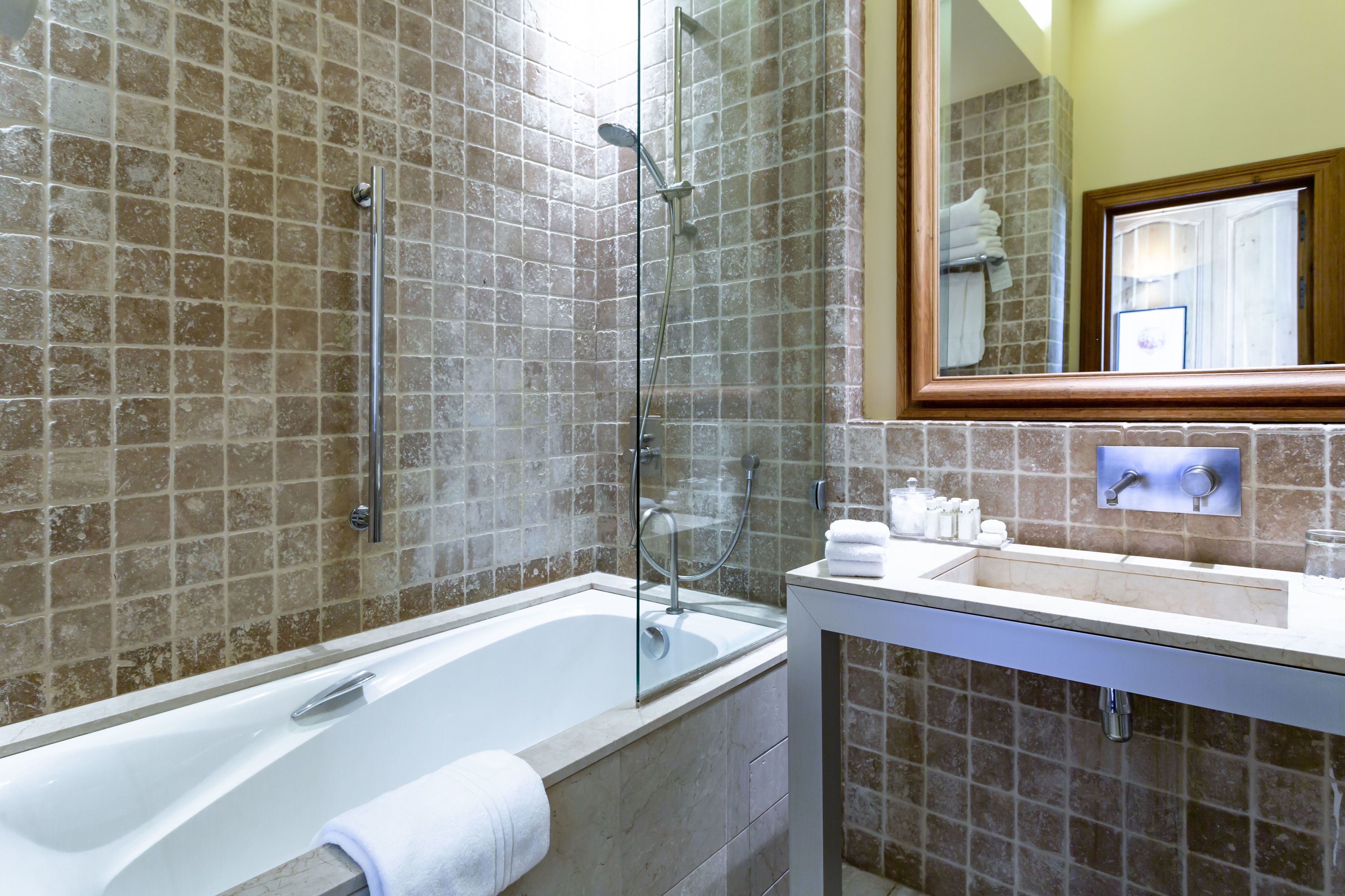 Un baño con bañera, ducha y lavamanos con artículos de aseo.