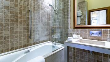 A bathroom with a bathtub, a shower, and a sink with toiletries.