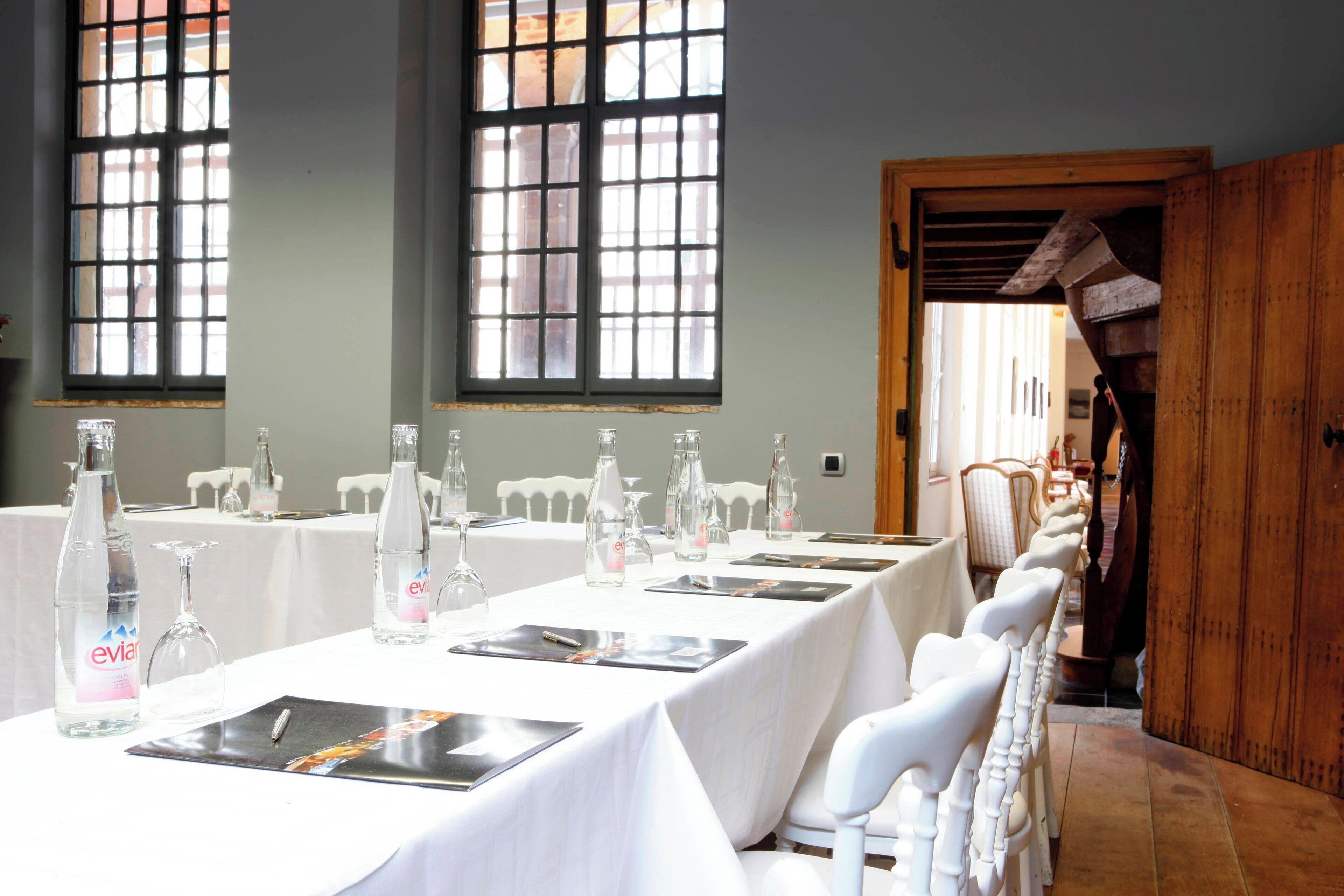 A conference room with long tables, chairs, and glassware.