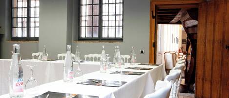 A conference room with long tables, chairs, and glassware.