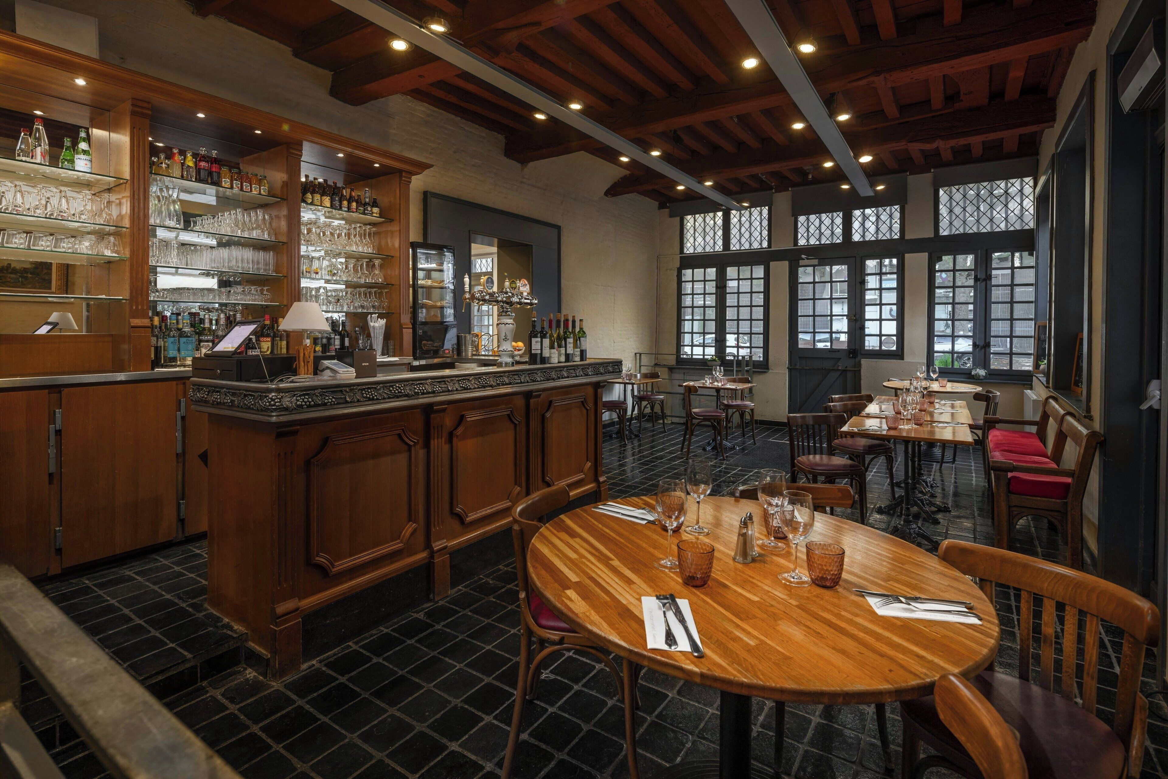 Een restaurant met houten meubels, een bar en grote ramen.