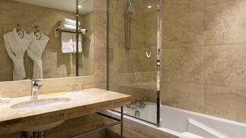 Een moderne badkamer met een marmeren wastafel, een douche met glazen wanden en een bad.
