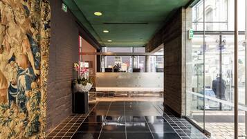 Un hall d’entrée avec un sol carrelé, un comptoir d’accueil et une grande fenêtre.