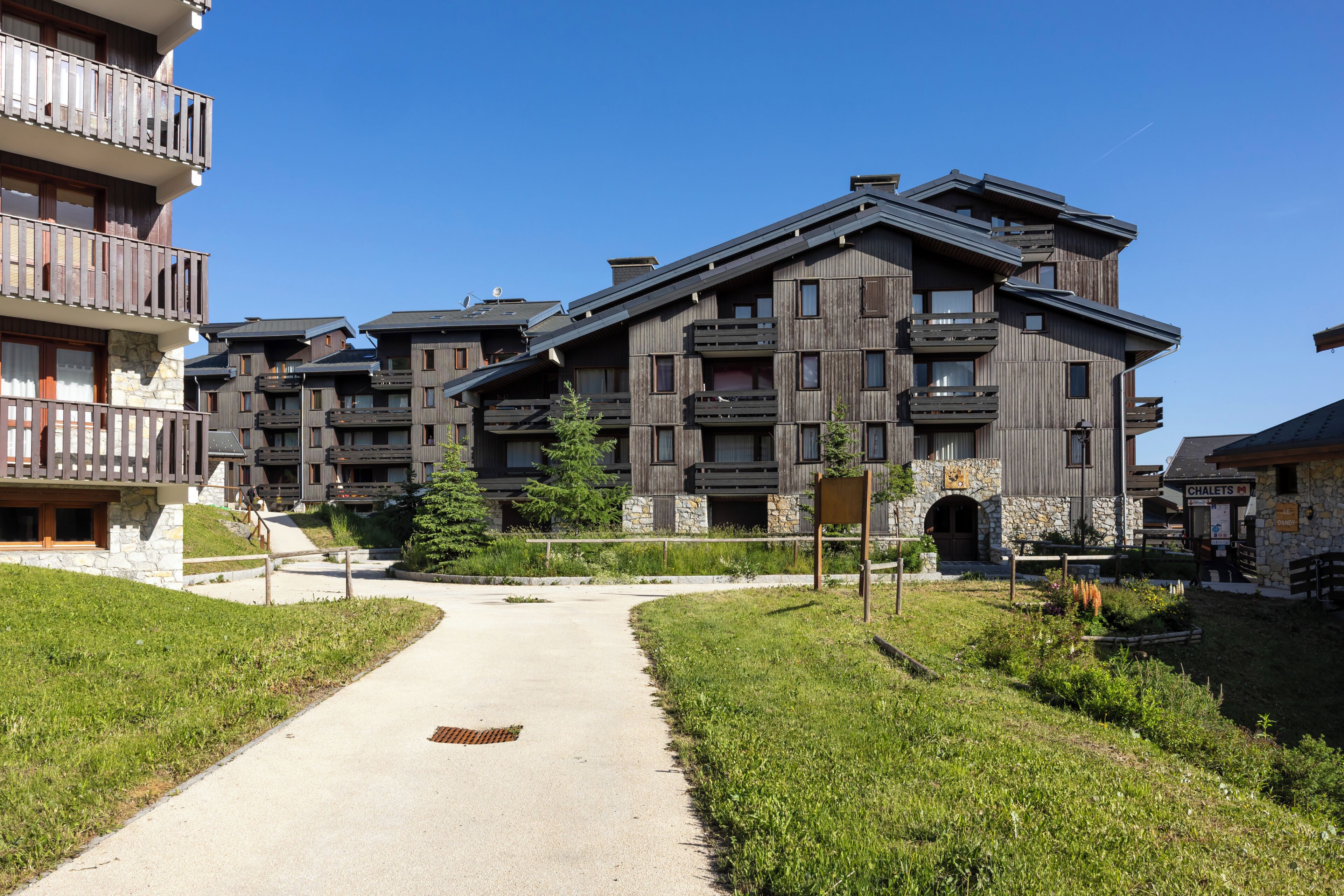 Ein mehrstöckiges Hotel mit Balkonen, einer Stein-Fassade und einem zentralen Weg.