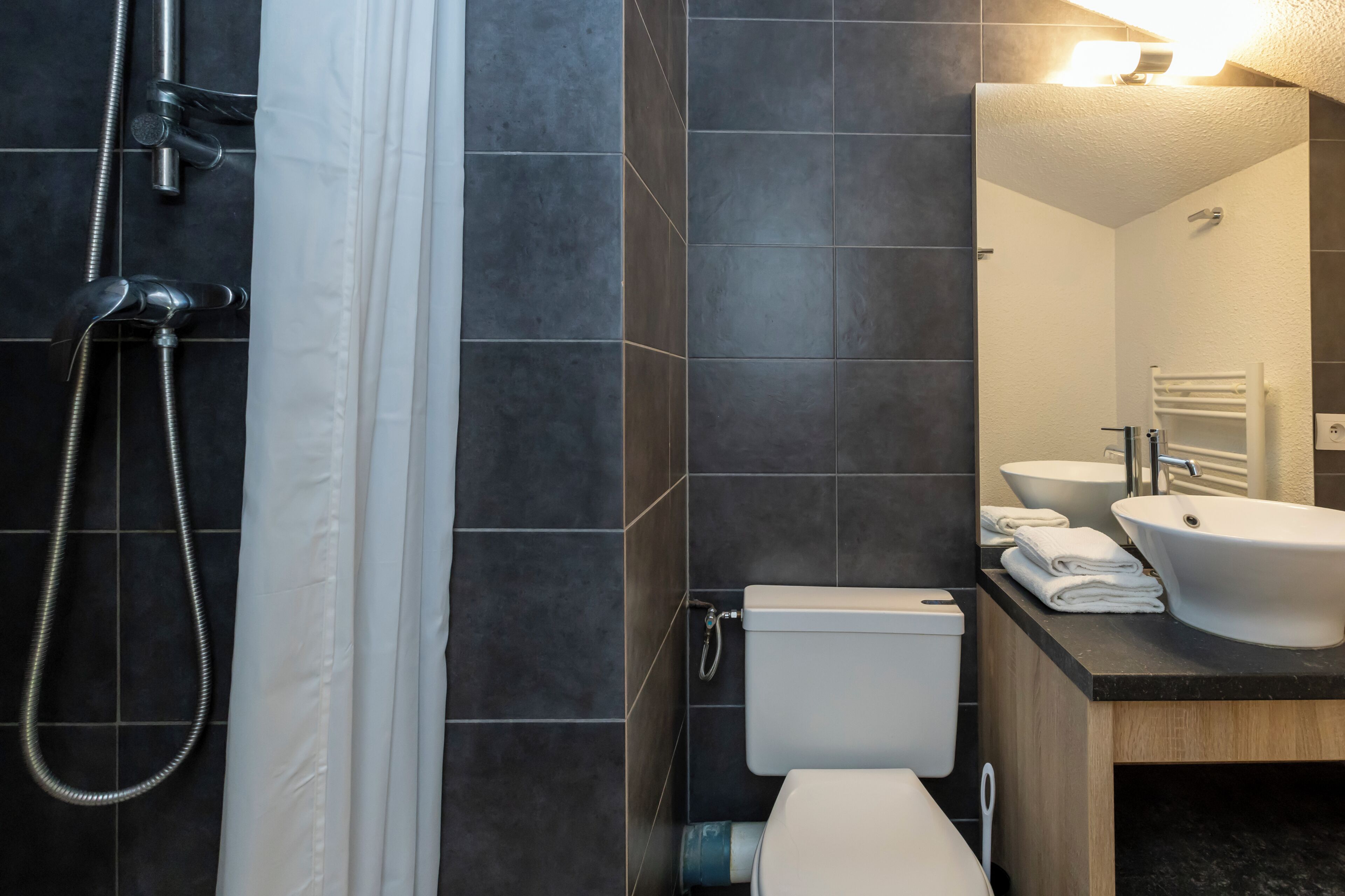 Une salle de bain moderne équipée d’une douche, de toilettes, d’un lavabo et d’un miroir.