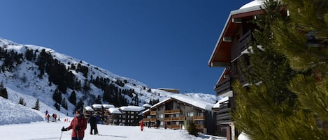 A ski resort with wooden buildings, snow-covered slopes, and skiers.
