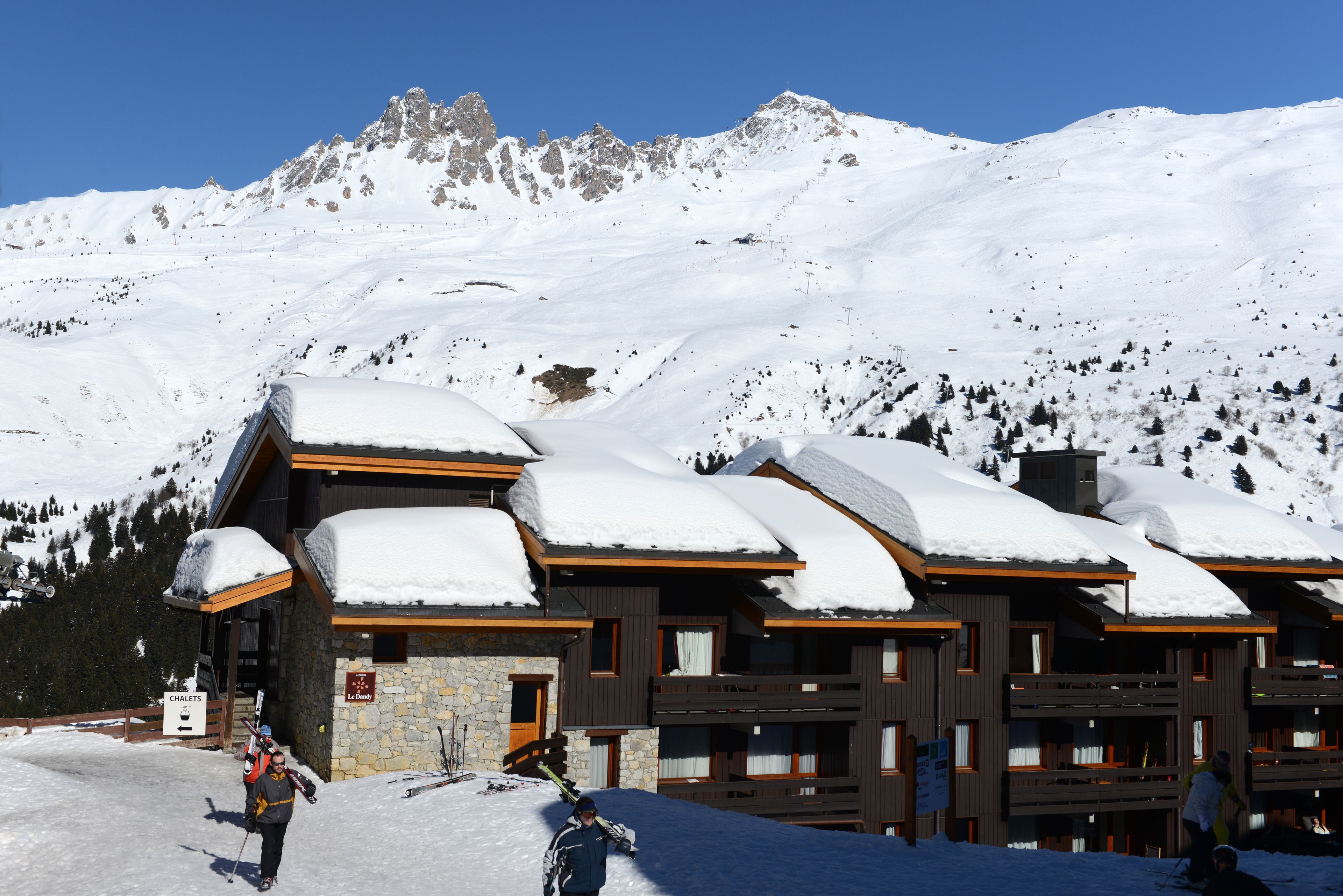 Eine Lodge mit mehreren Balkonen und einer Steinfassade, umgeben von schneebedeckten Bergen.