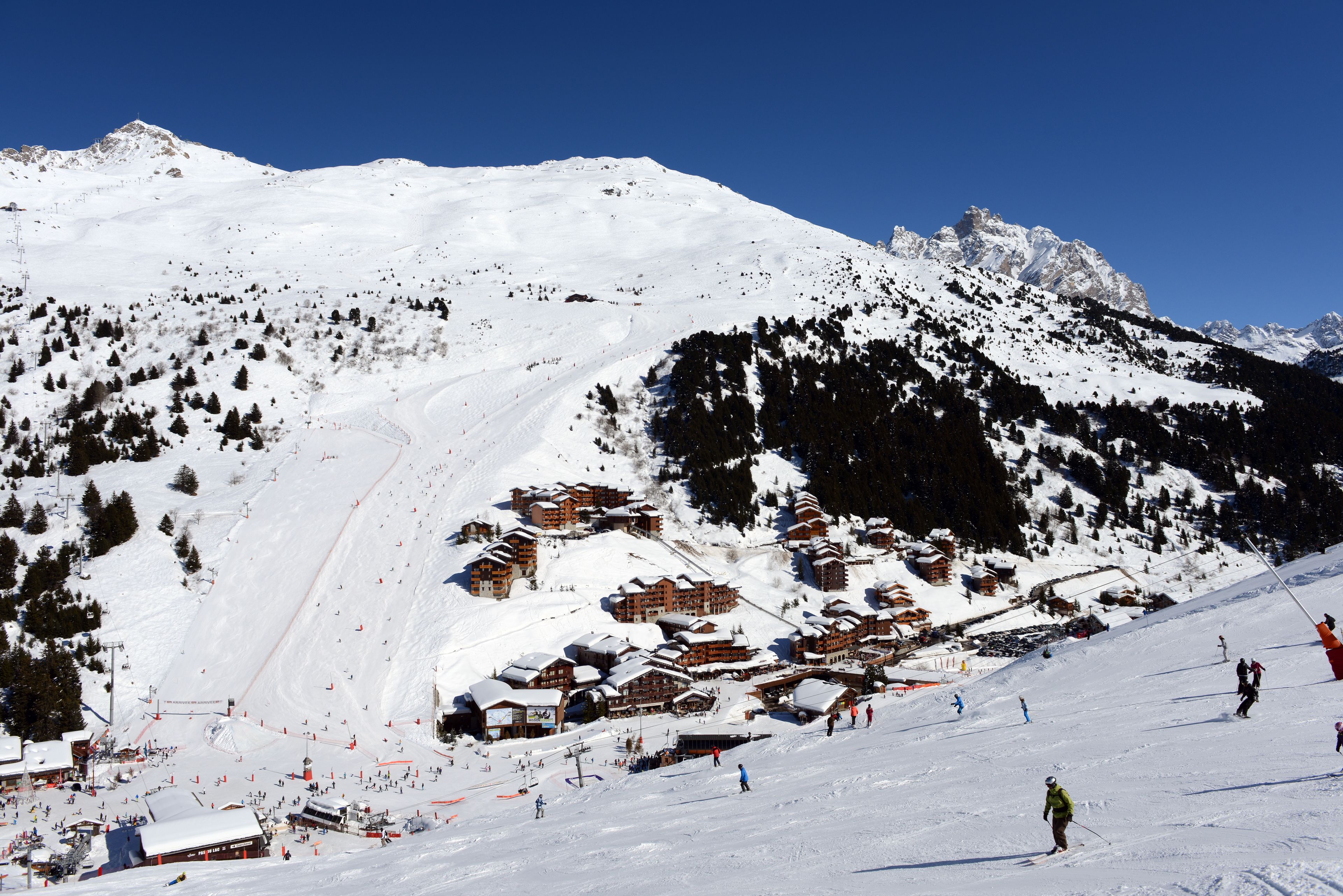 Een met sneeuw bedekte berg met skigebouwen en een piste.