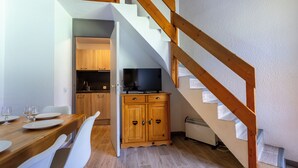 Un coin repas avec une table et des chaises en bois, une cuisine avec des meubles en bois et un escalier avec des rampes en bois.