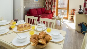 A breakfast setup with croissants, orange juice, and a loaf of bread on a table. - Résidence Odalys Les Lumières de Neige (Valmeinier)