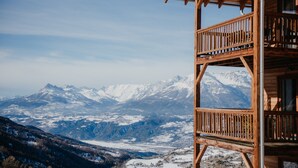 A wooden cabin with a balcony overlooking snow-covered mountains. - Résidence Sunêlia Les Logis d'Orres (Les Orres)
