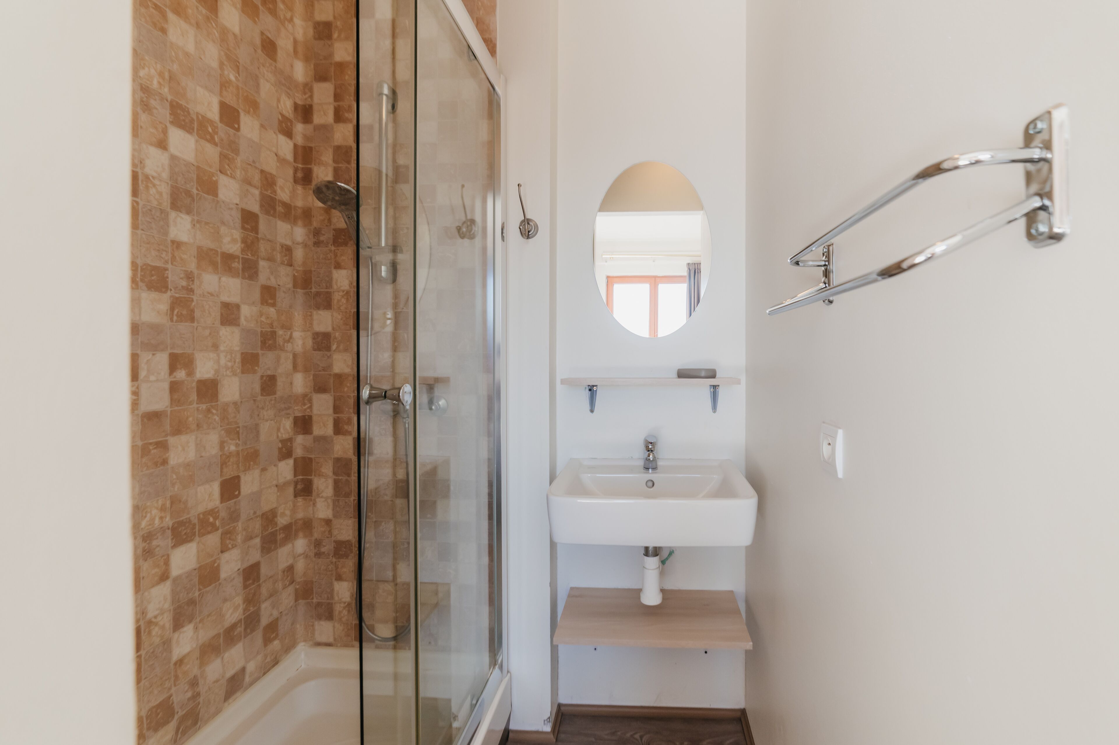Un baño con cabina de ducha de vidrio, un lavabo blanco y un espejo.