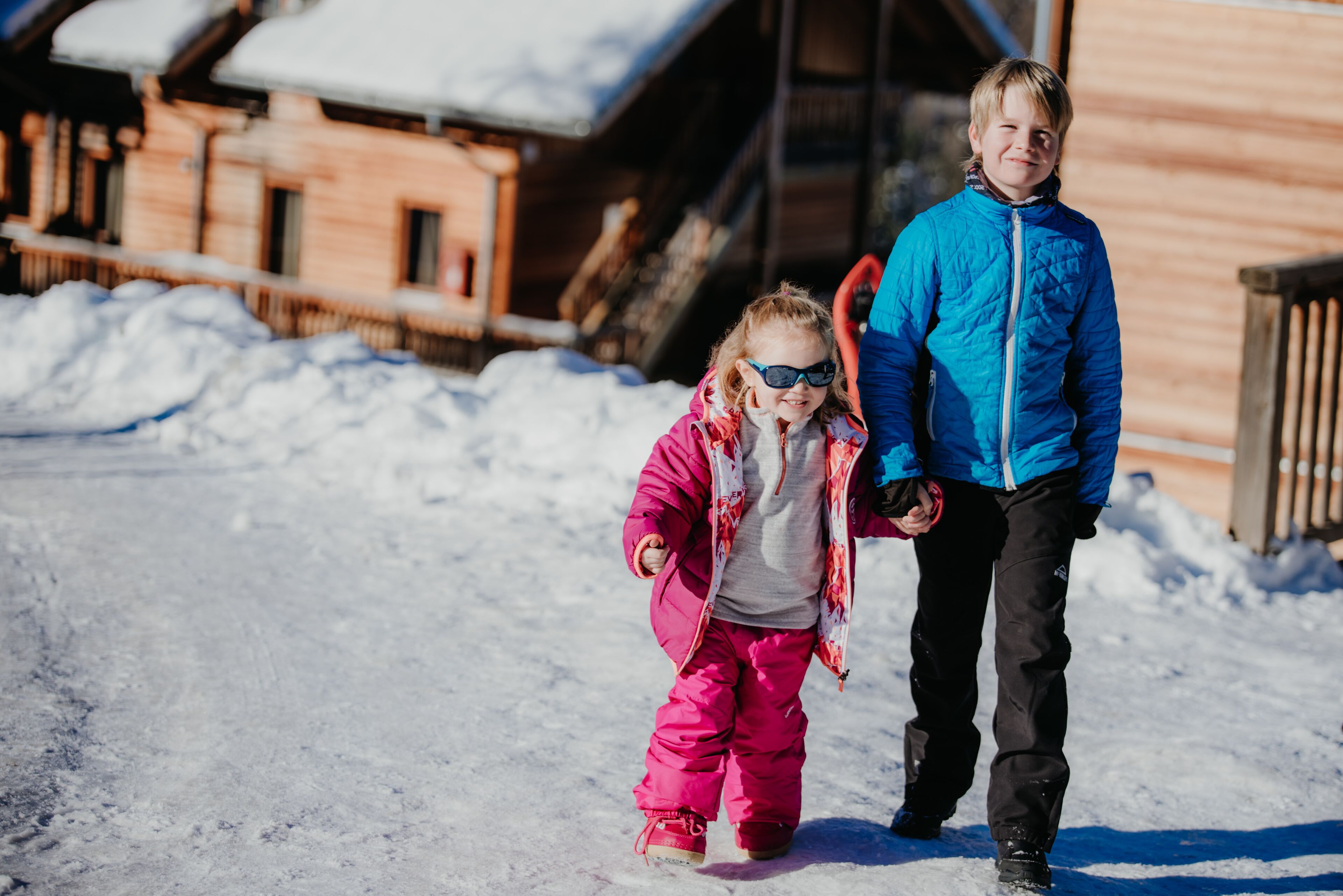 Una baita di legno con tetto innevato e veranda in legno.
