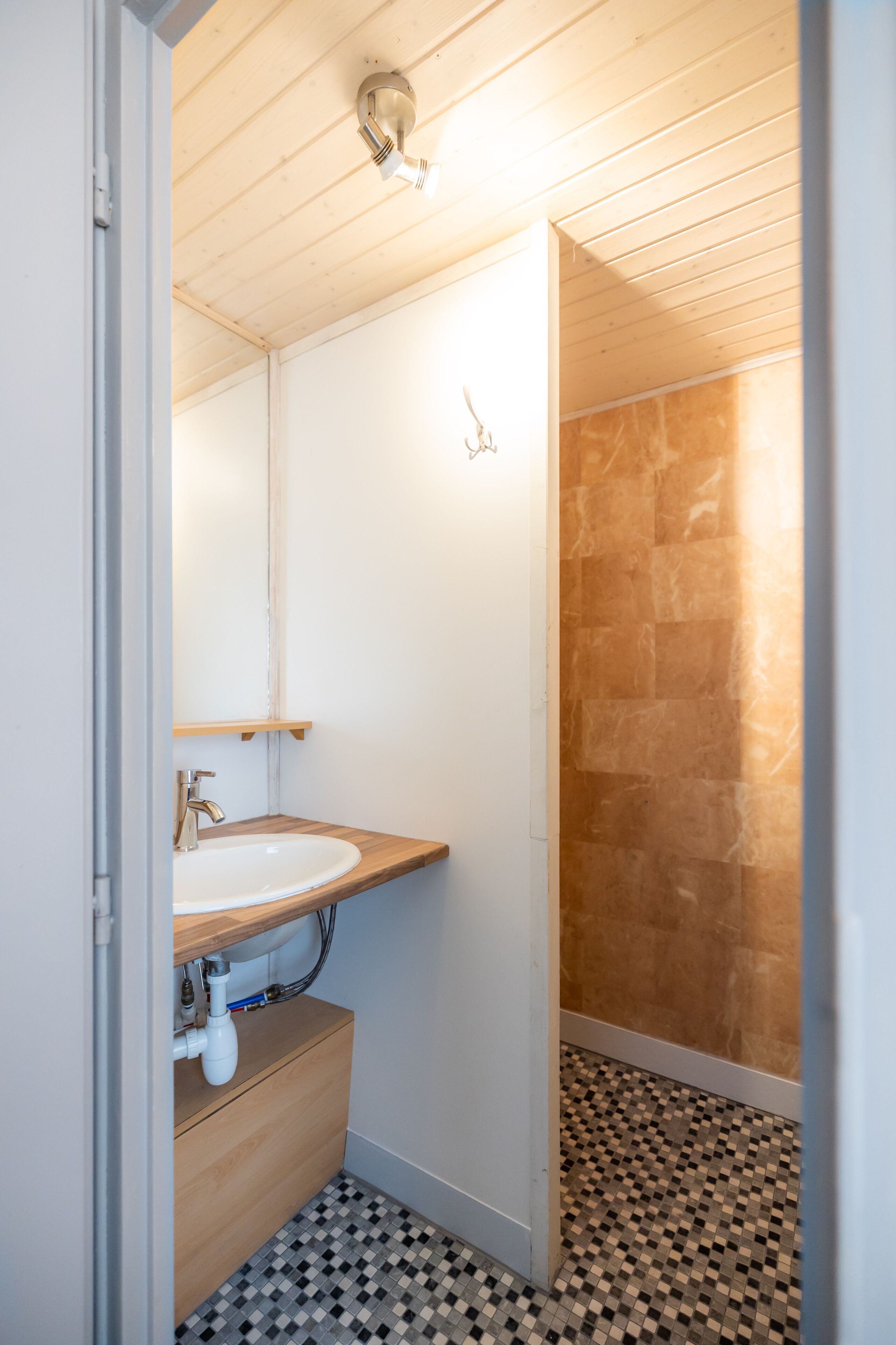 Une salle de bain avec un meuble-lavabo en bois, un lavabo blanc et un sol carrelé.