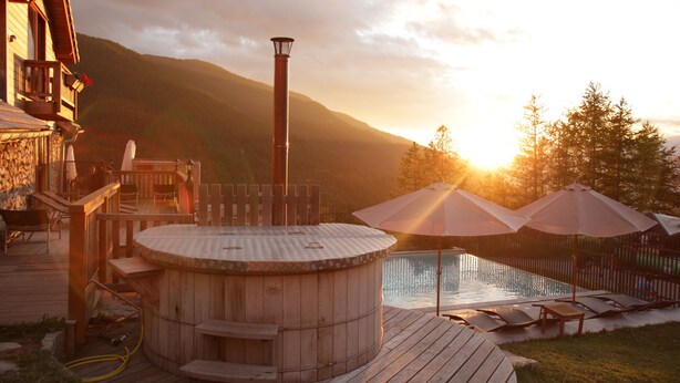 A wooden deck with a hot tub, lounge chairs, and umbrellas. - Résidence Sunêlia Les Logis d'Orres (Les Orres)