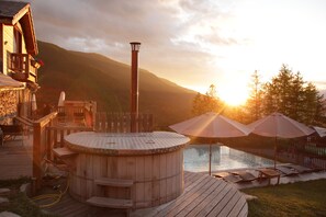 A wooden deck with a hot tub, lounge chairs, and umbrellas. - Résidence Sunêlia Les Logis d'Orres (Les Orres)