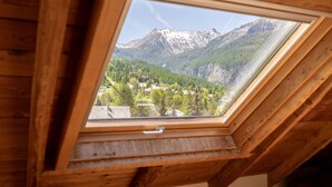 A skylight with a view of a mountainous landscape, wooden beams, and a clear sky. - Résidence Sunêlia Les Logis d'Orres (Les Orres)