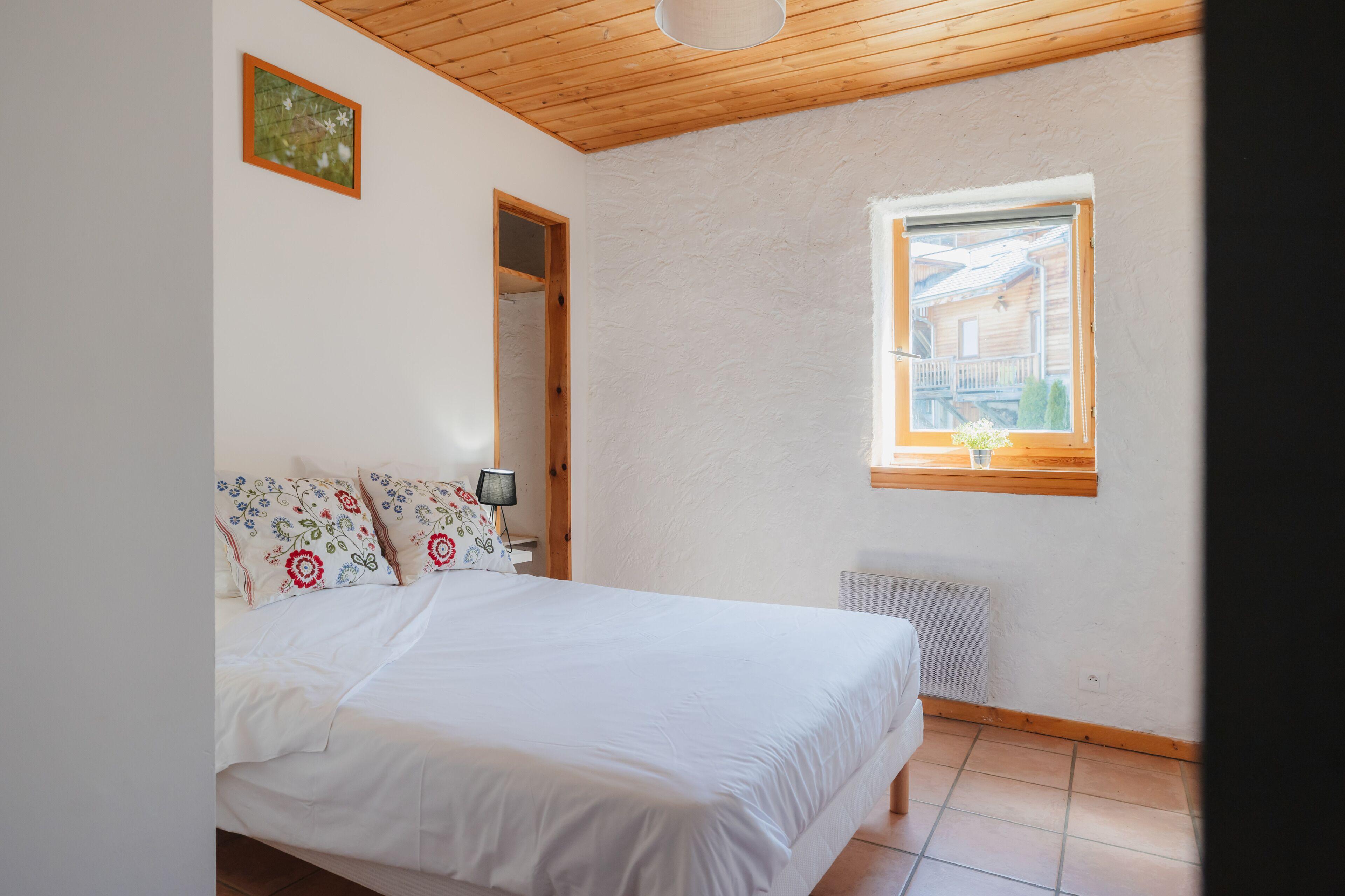 A bedroom with a bed, a window, and a door.