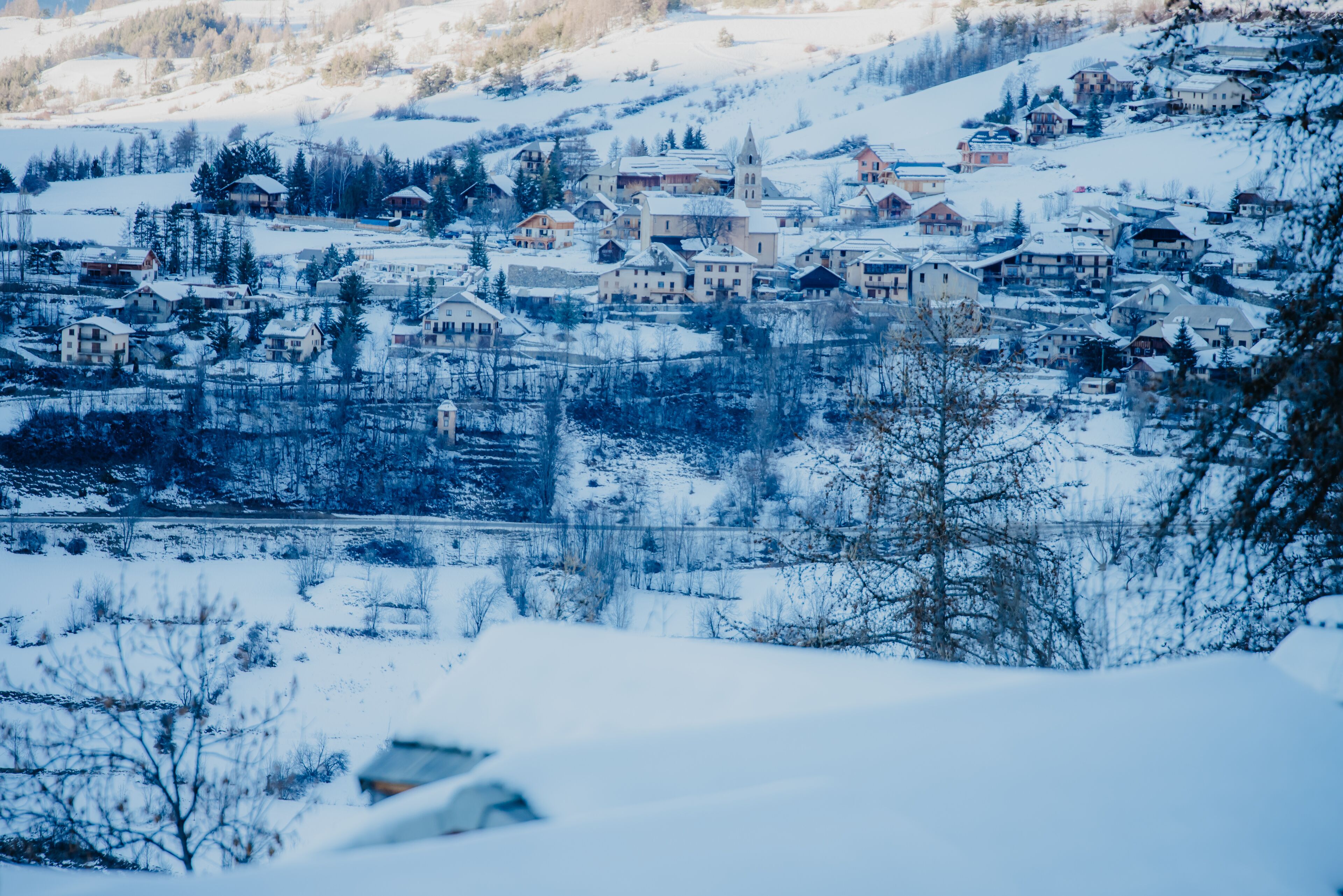 Un pueblo cubierto de nieve con casas e iglesia.