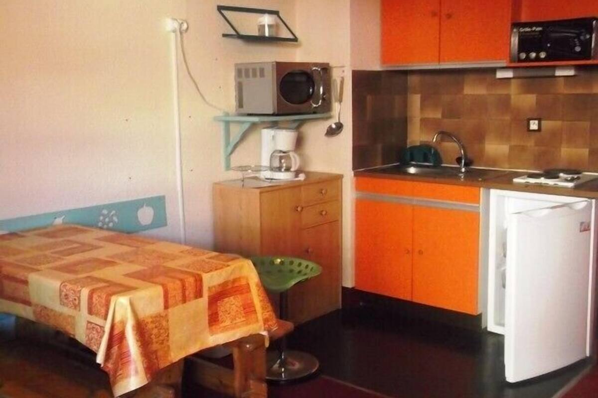 Eine kleine Küche mit Mikrowelle, Kaffeemaschine und einem Kühlschrank.