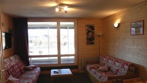 A cozy room with two sofas, a small table, and a window with curtains.