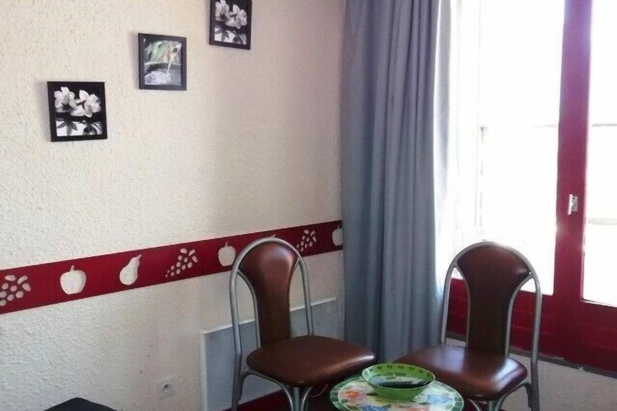 Ein Zimmer mit zwei Stühlen, einem Tisch, einer roten und weißen Dekorationsleiste und drei gerahmten Bildern an der Wand.