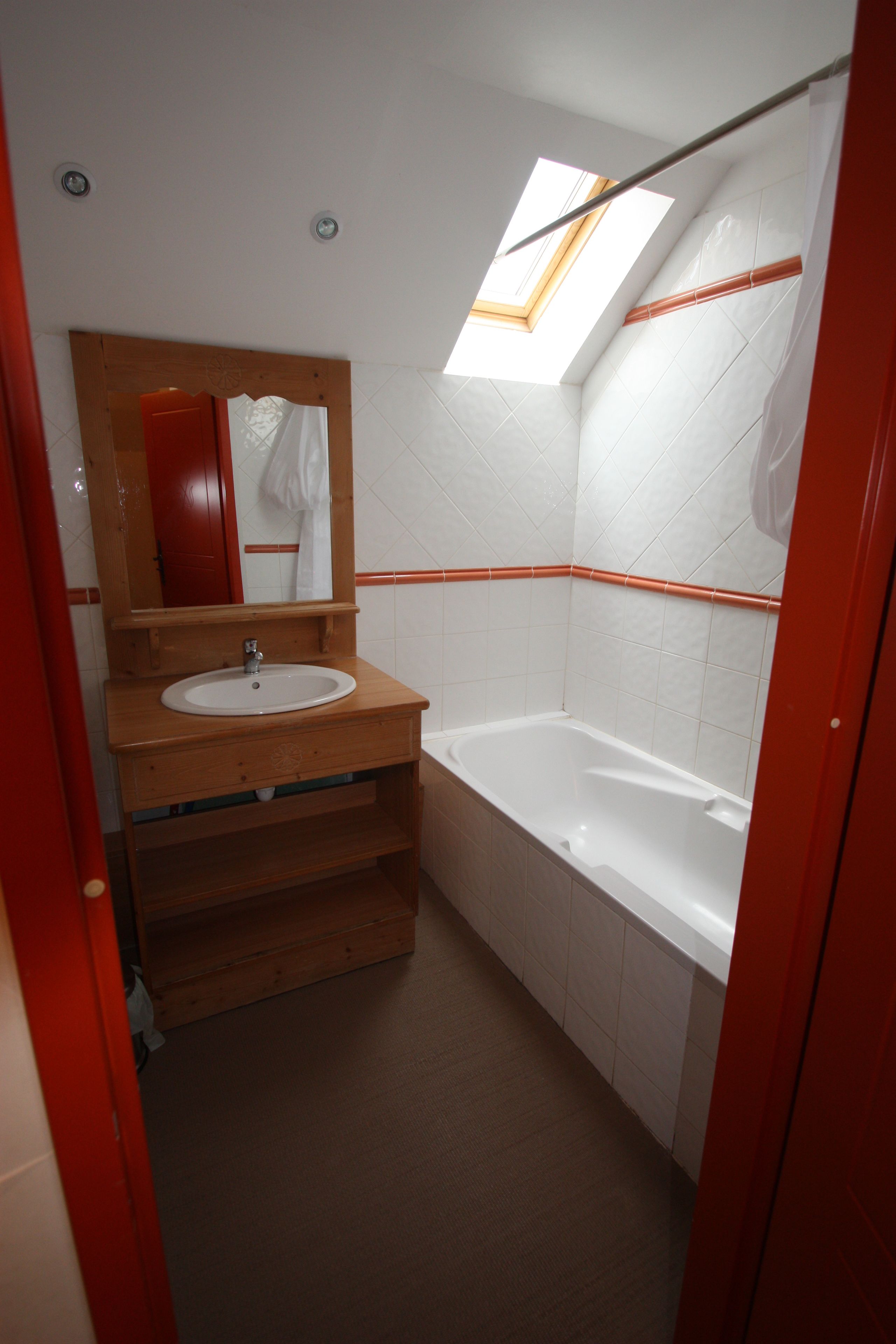 A bathroom with a wooden vanity, white sink, and a bathtub.