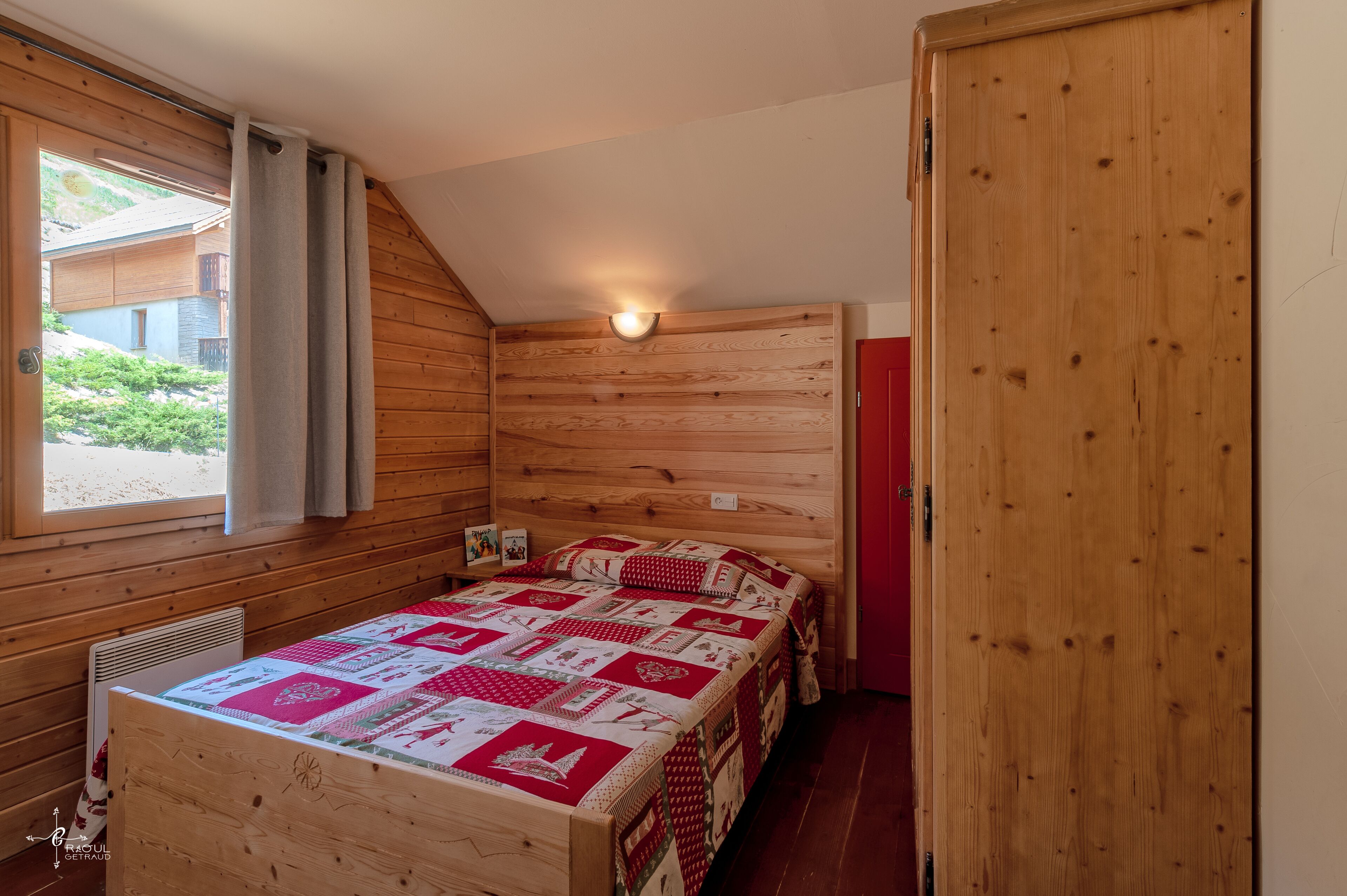A wooden room with a bed, a window, and a door.