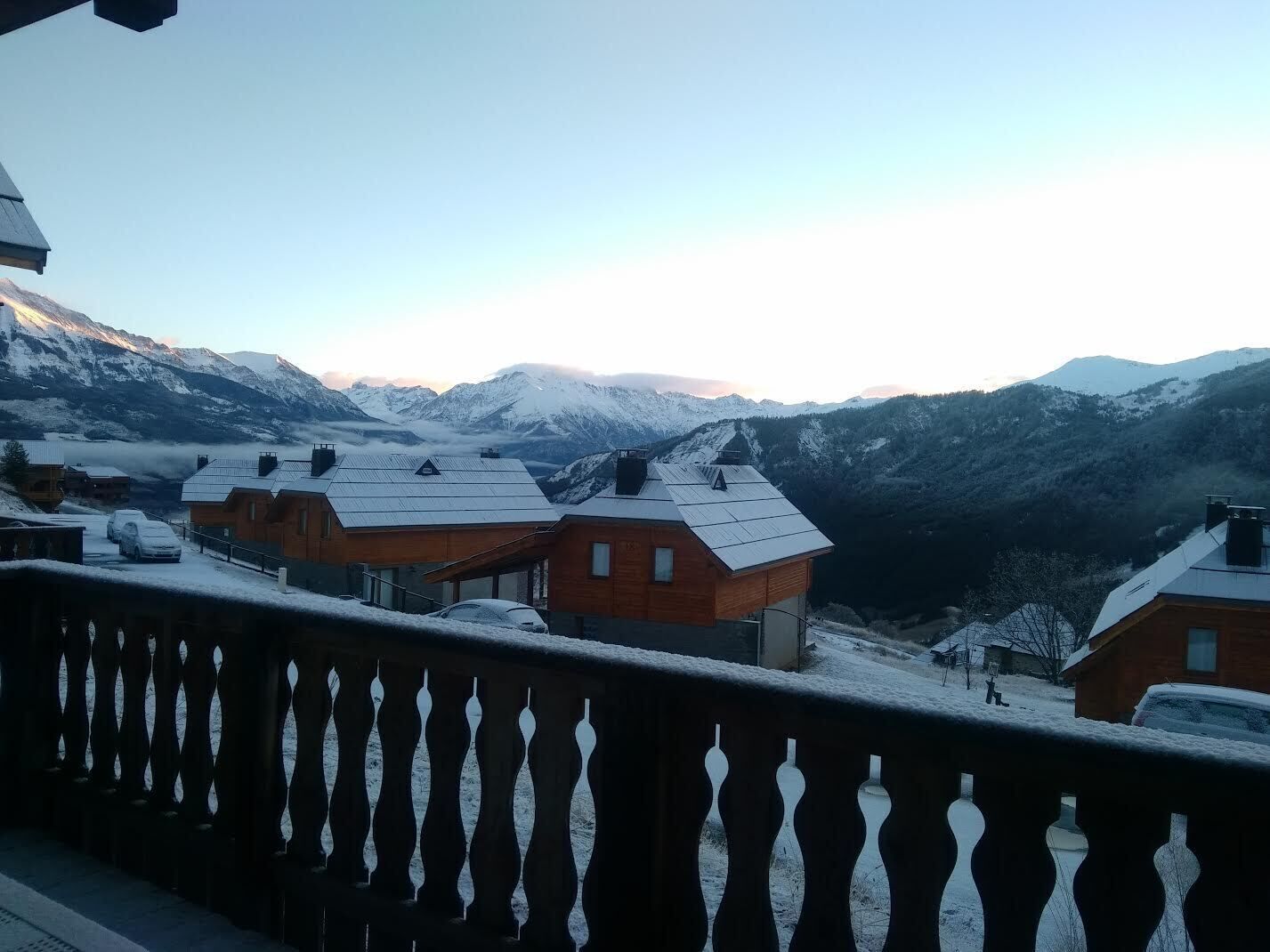 Un albergue de montaña con varias cabañas de madera, cada una con techo inclinado y paneles solares.