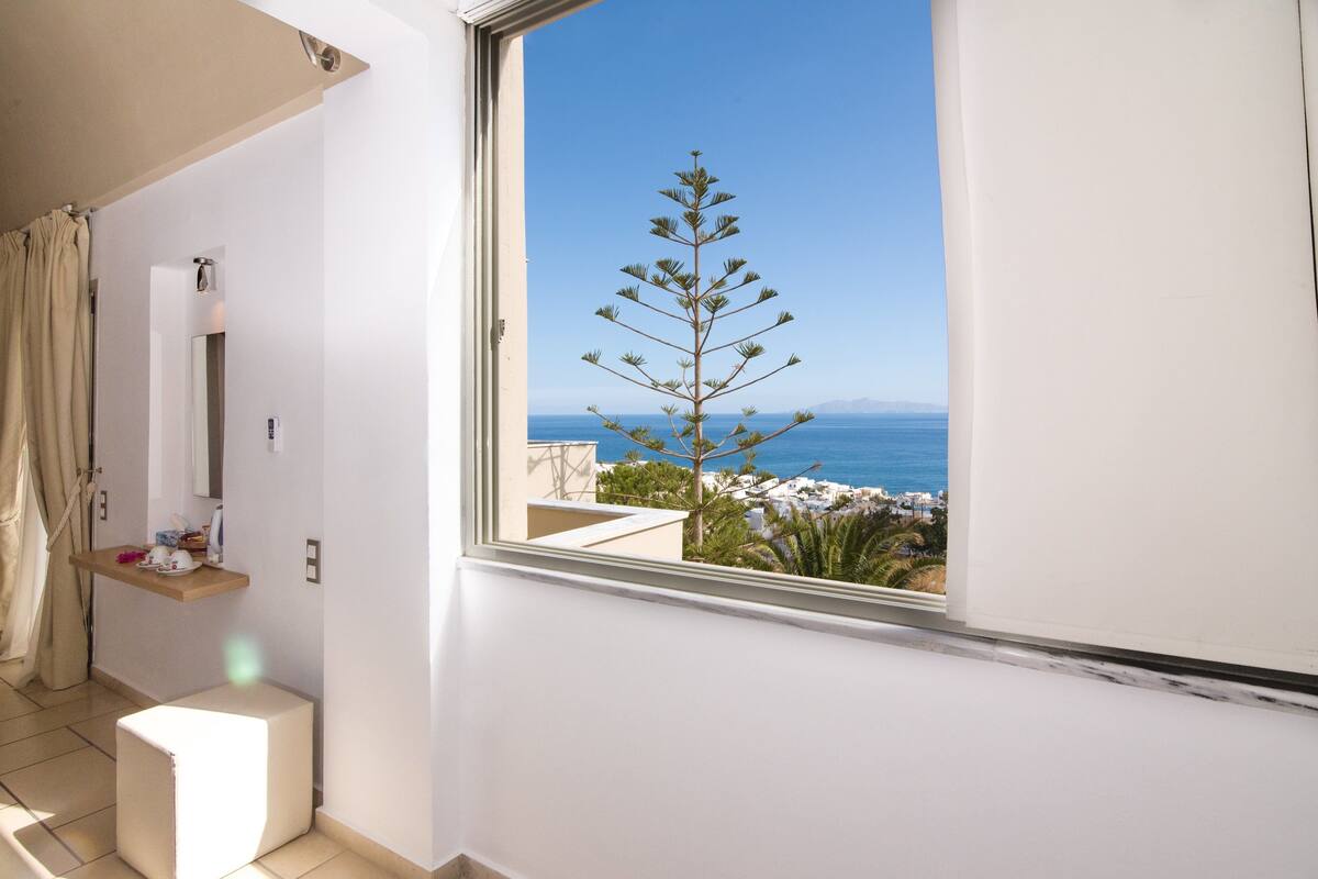 A balcony with a view of the sea and a tree.