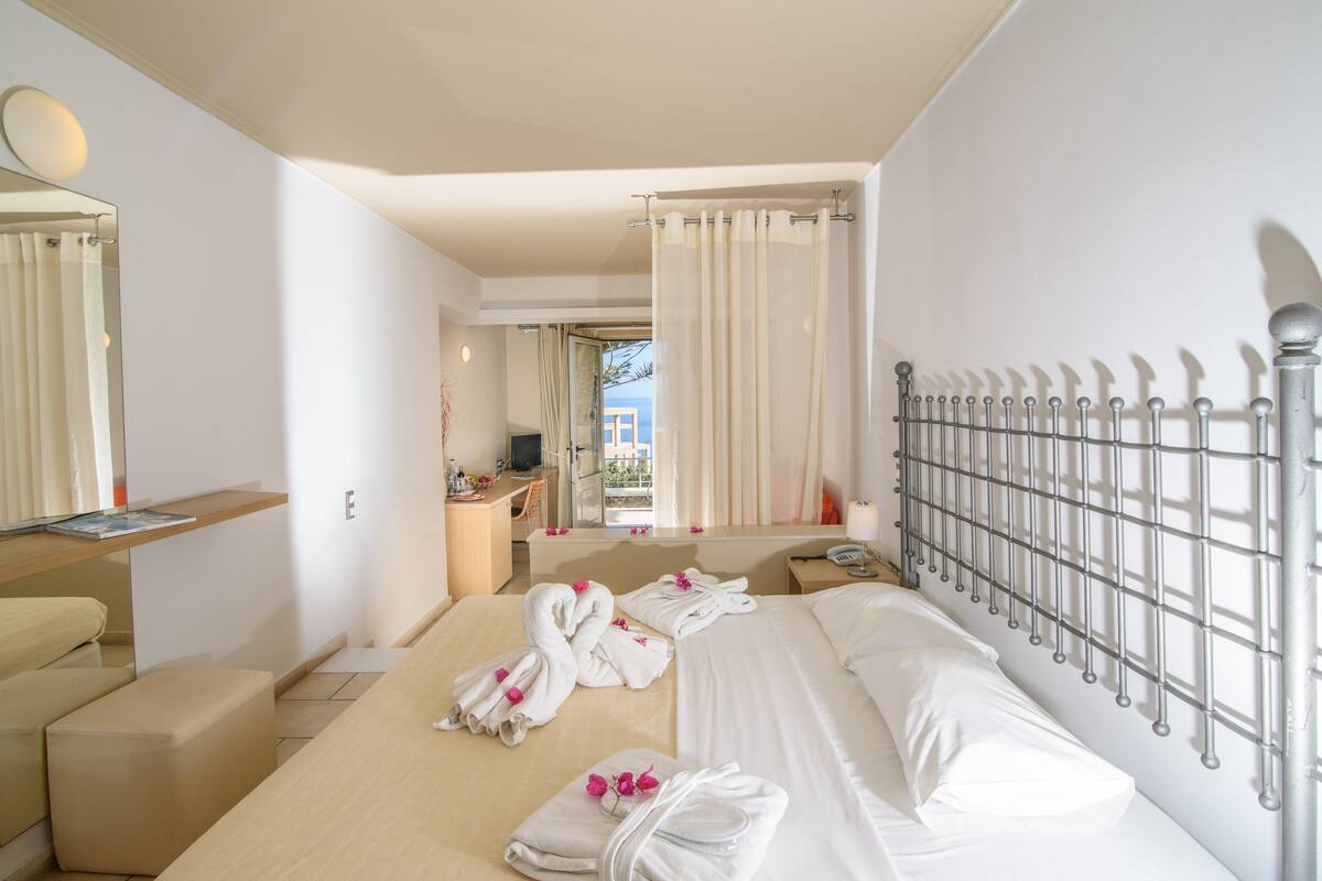 A hotel room with a bed, a desk, a chair, and a bathroom visible through an open door.