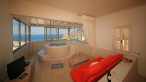 Una sala de estar moderna con un ventanal grande, un jacuzzi y un sofá rojo.