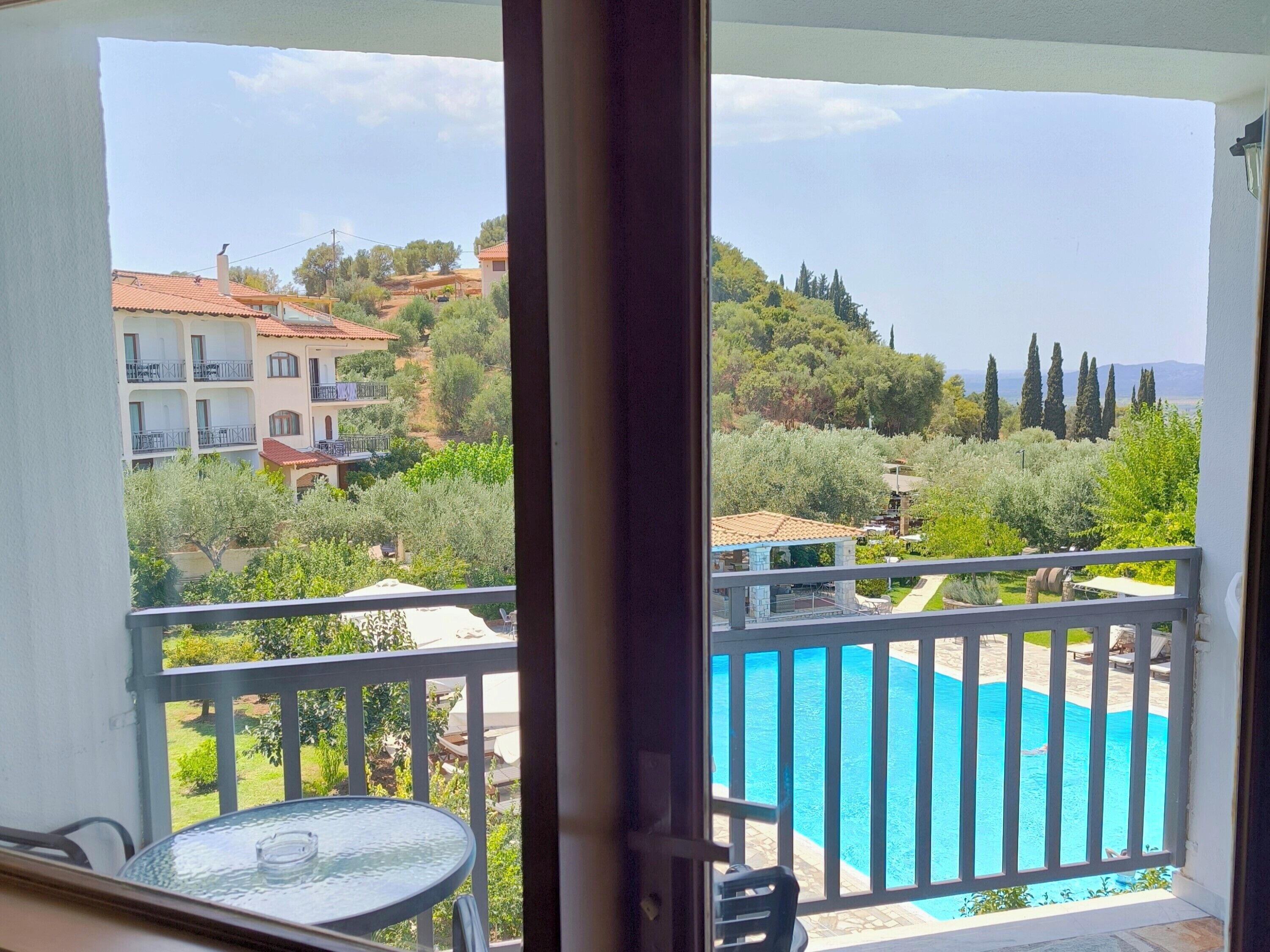 Un balcón con vistas a una piscina y vegetación circundante.