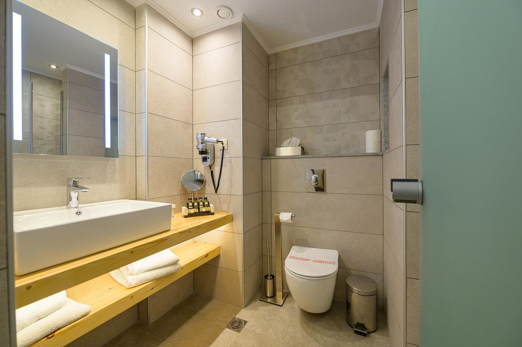 Un baño moderno con un lavamanos grande, un espejo y un inodoro.