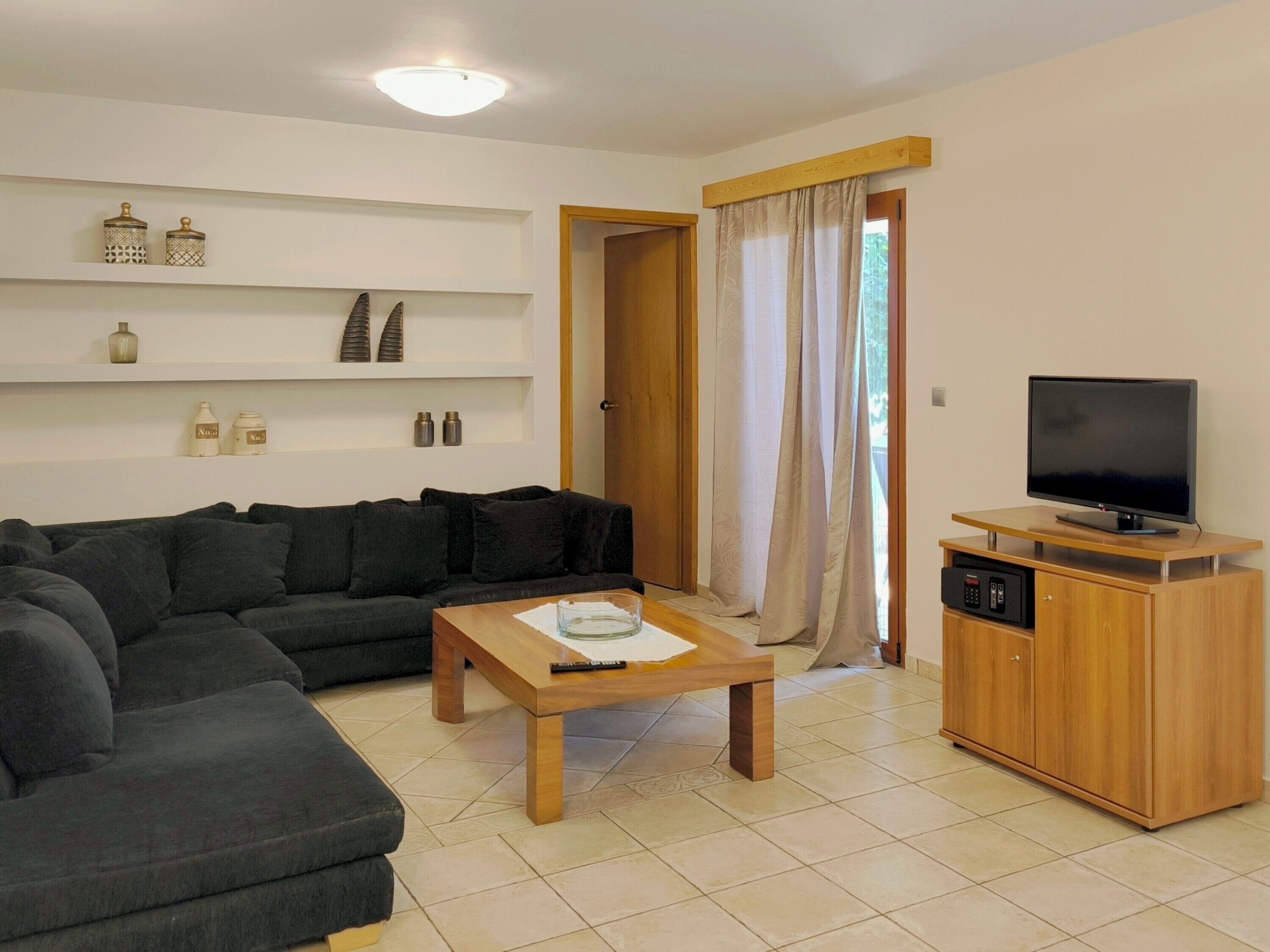 A living room with a sofa, a coffee table, a TV on a wooden stand, and a cabinet with a microwave.
