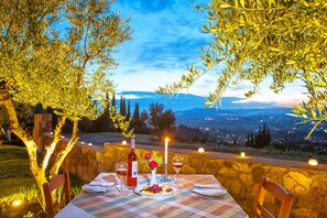 Mesa de comedor al aire libre con vista a un paisaje urbano al anochecer.