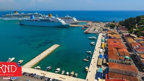 Une ville côtière dotée d’un port de plaisance, où l’on peut voir des navires de croisière et un ferry amarré.
