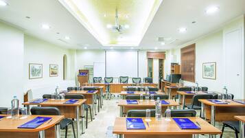 A conference room with multiple tables, chairs, and a podium.