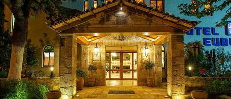 A stone building with a tiled entrance, a wooden roof, and a sign that reads "HOTEL EUROPA".