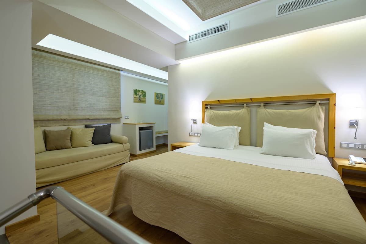Habitación de hotel con cama, sofá, escritorio y una pequeña kitchenette.
