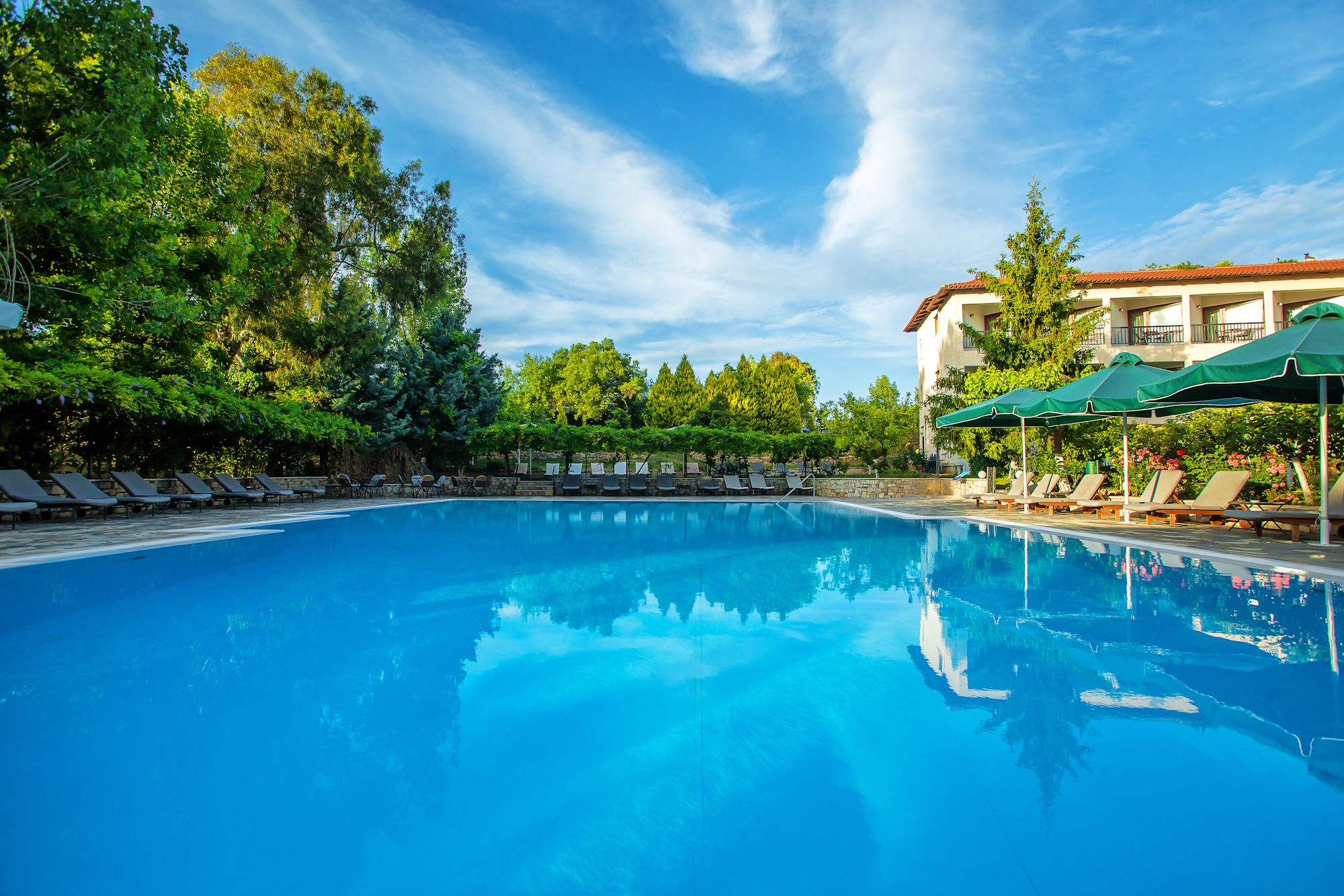 Een buitenzwembad, ligstoelen bij het zwembad