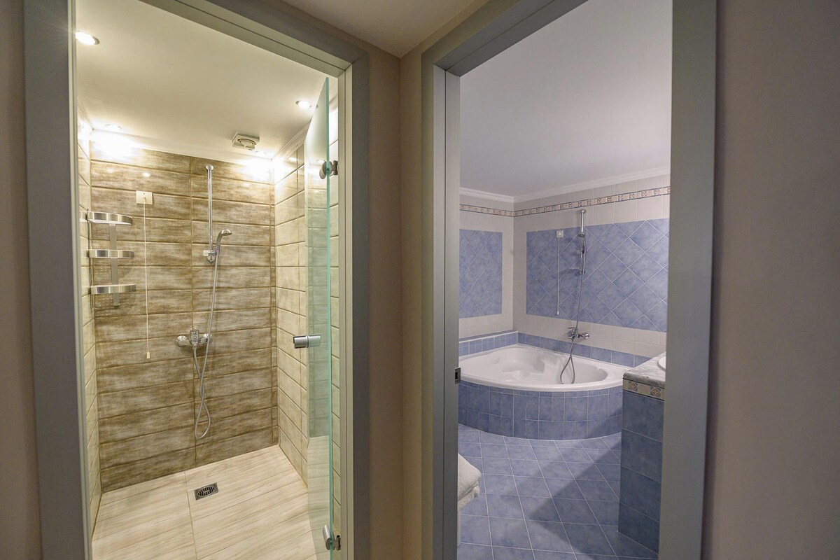 Un baño moderno con ducha envuelta en vidrio, una bañera independiente y paredes revestidas de azulejos.