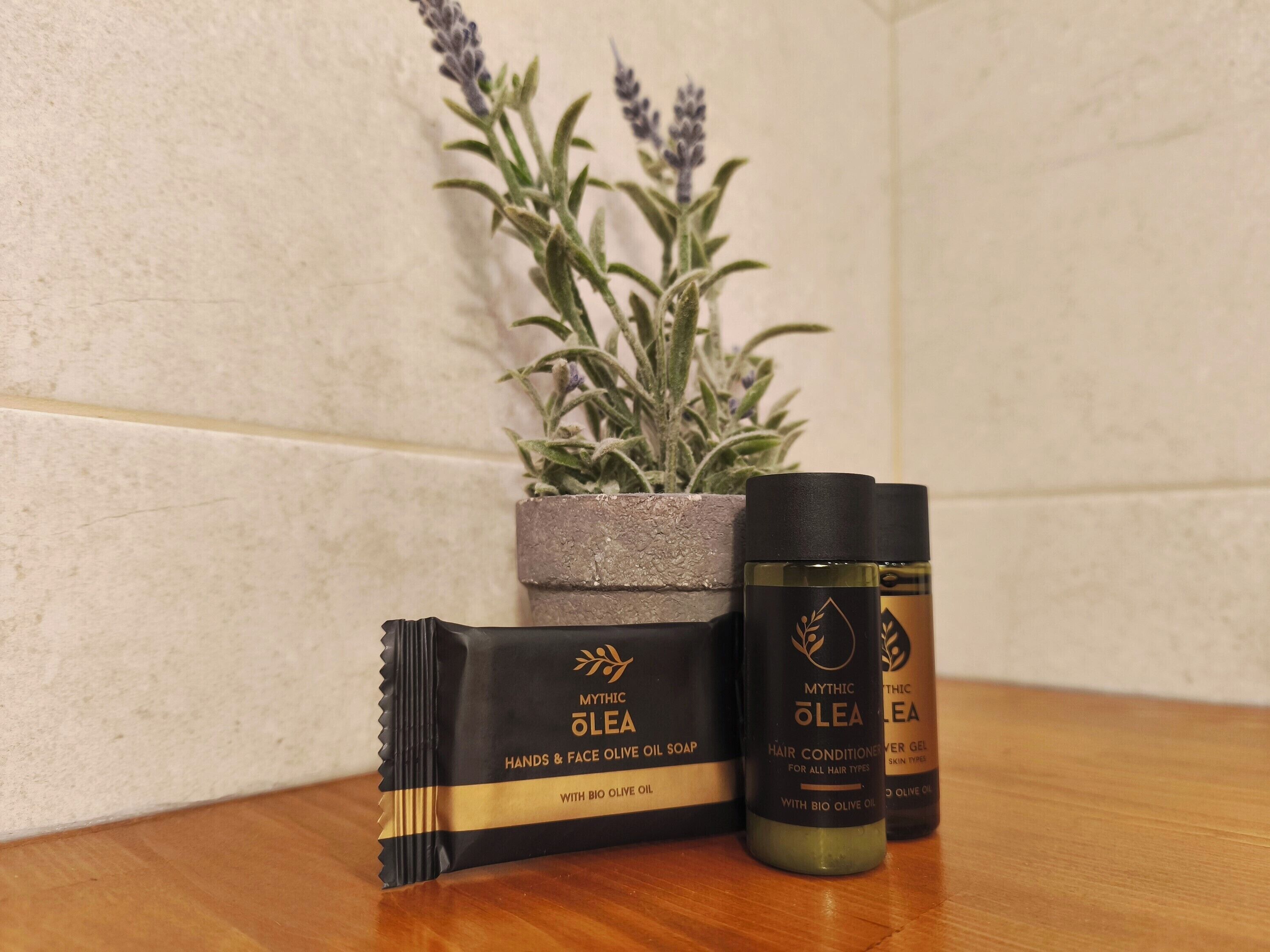 A bathroom with a potted lavender plant, a bar of soap, and two bottles of hair conditioner.