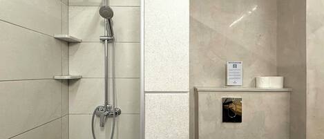 Une salle de bain avec une douche, des toilettes et une petite étagère sur laquelle se trouvent une serviette et un panneau.