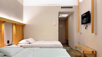 Ein Hotelzimmer mit zwei Betten, einem Deckenventilator, einem an der Wand montierten Fernseher und einer hölzernen Bank.