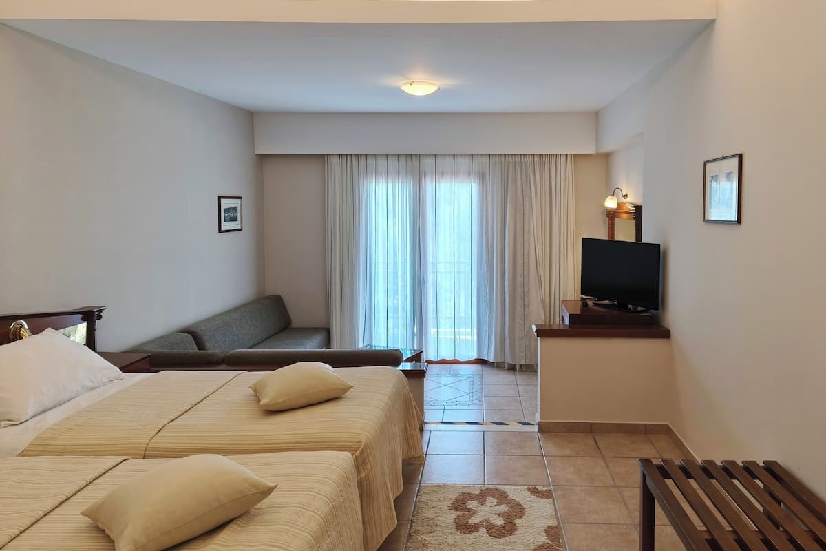 Una habitación de hotel con dos camas, un sofá, un televisor y un escritorio.