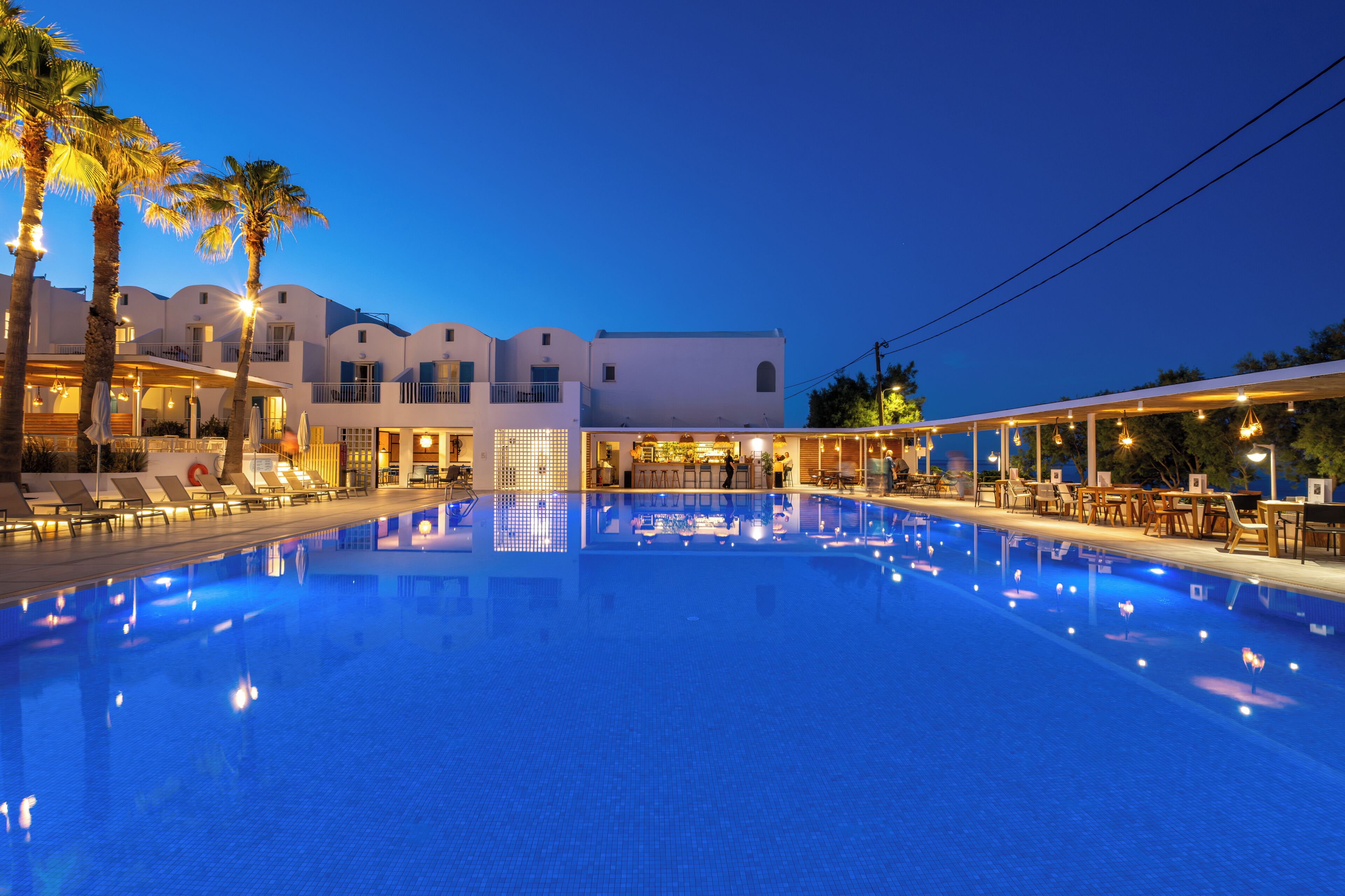 Una piscina al aire libre, sombrillas, sillones reclinables de piscina